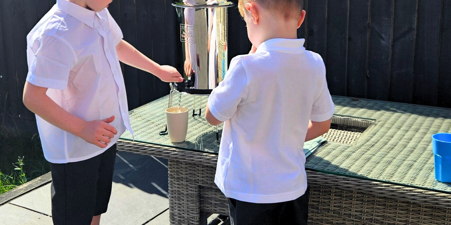 children pouring water into a cup in garden