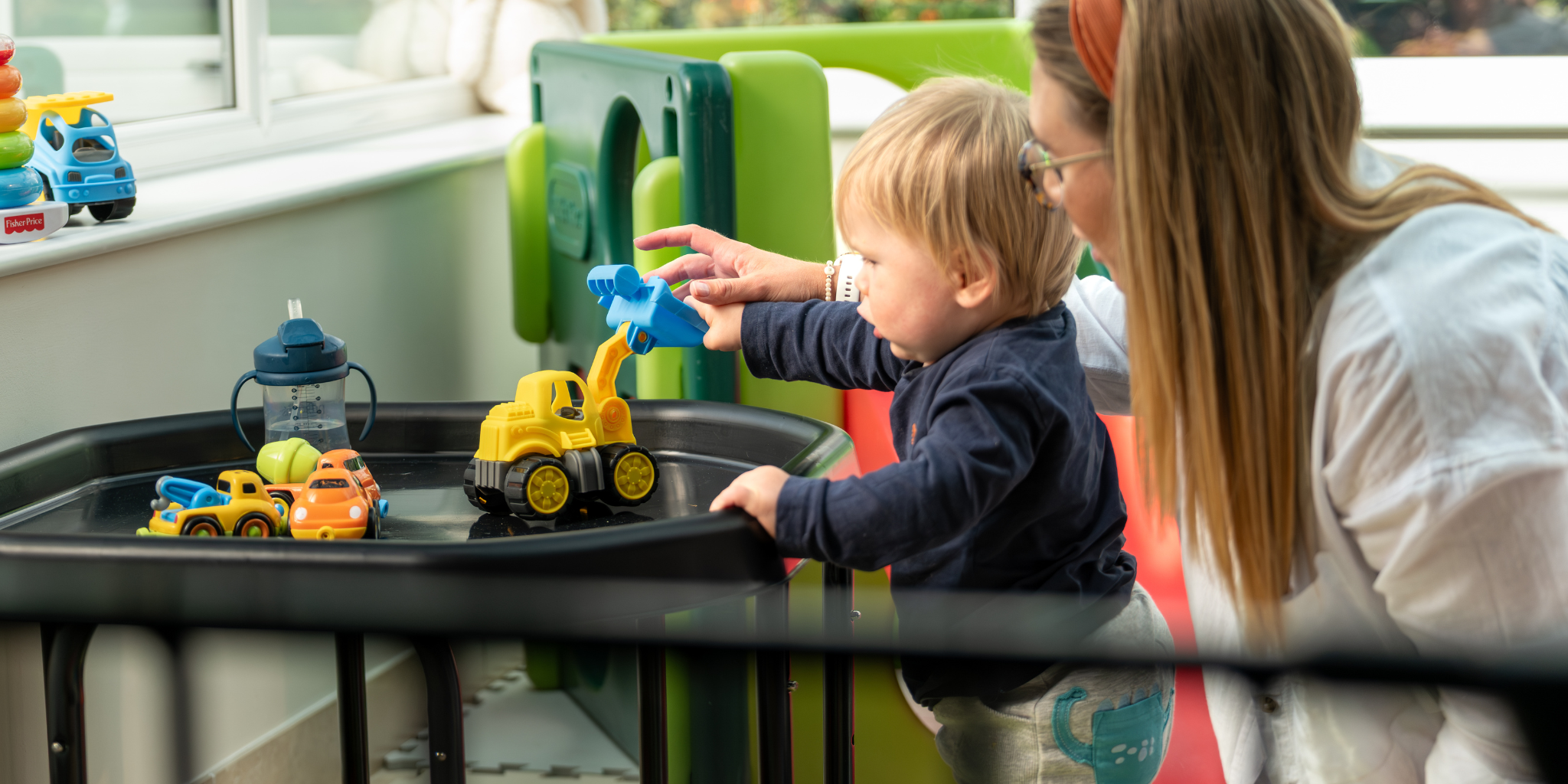 mother and son playing with plastic toys in play area of house