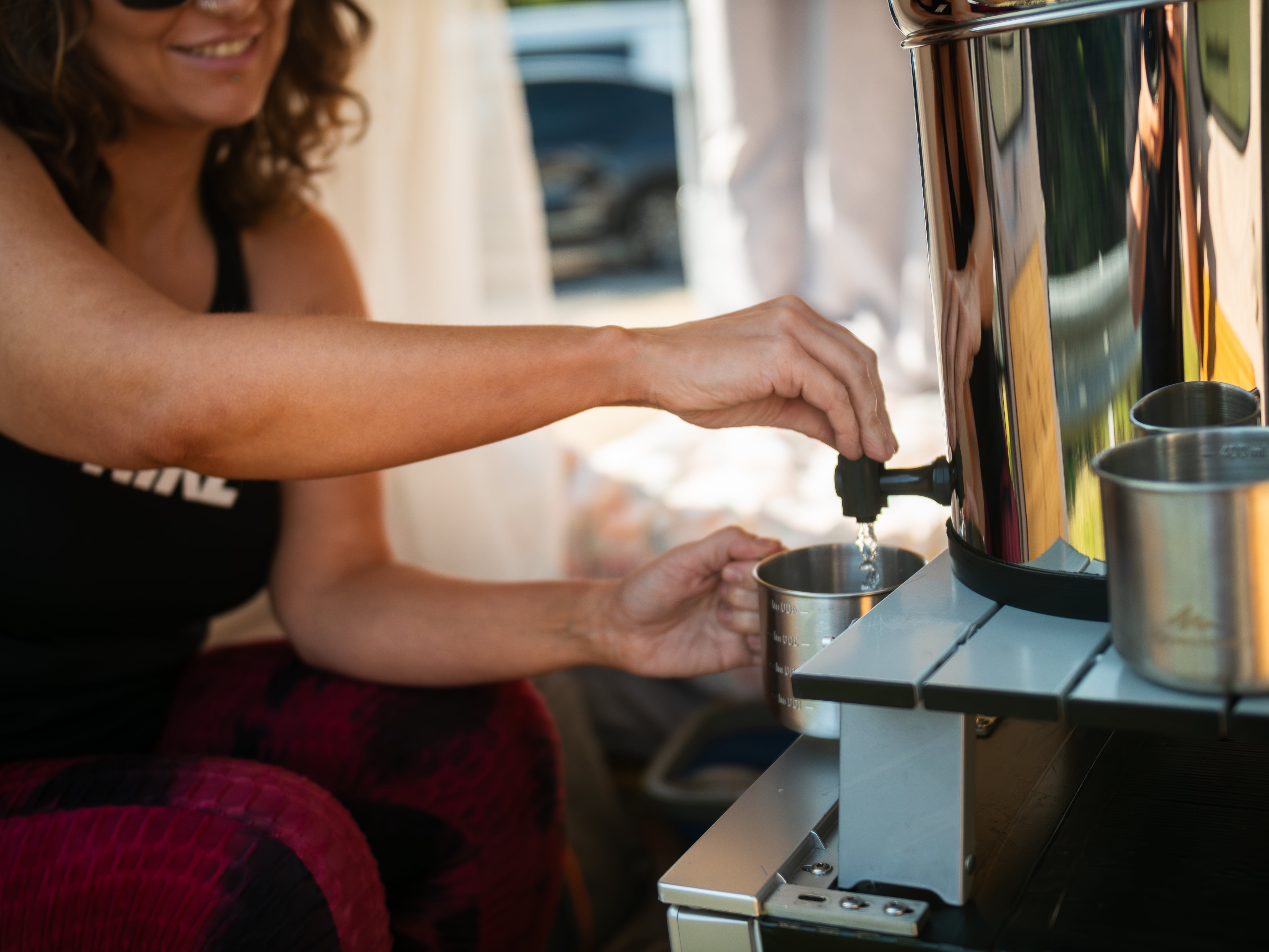 hands pouring water from a filter system into a cup
